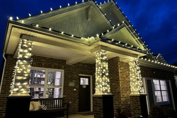 Porch columns wrapped in warm white Christmas lights on a brick home in Liberty Township, OH