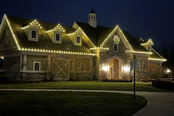 Warm white Christmas lights outlining the roofline and dormers of a commercial clubhouse in Loveland, OH