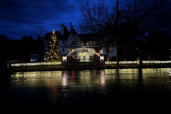 Lit fence line and lit evergreen tree in front of a Tudor style estate in Mariemont, OH