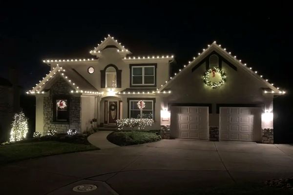 Warm white roofline Christmas lights with lit wreaths on a two-story home in Miami Heights, OH