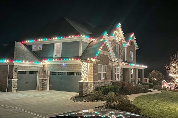 Two-story home with red, green, and white C9 Christmas lights along the roofline
