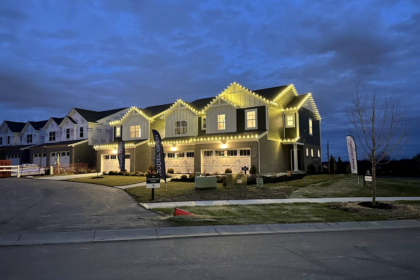 Row of townhomes with warm white Christmas lights on every roof peak at dusk, installed by Liberty Christmas Lights
