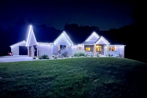 Ranch home with bright white Christmas lights on every roof peak at night