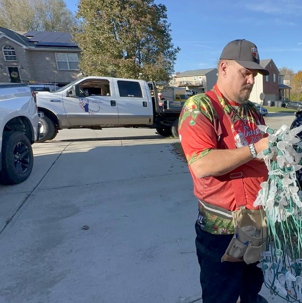 DJ sorting pre-built C9 light strands in a customer's driveway before an install